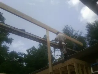 Carpenter setting a ridge beam over a new addition frame — Ice Dam Removal by Roofing Brothers in Conover
