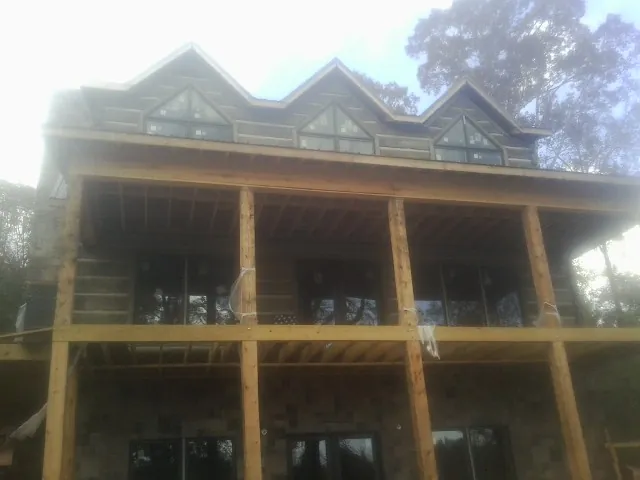 Dormers and porch framing on a large log home under construction — Roof Coating work by our crew in Conover