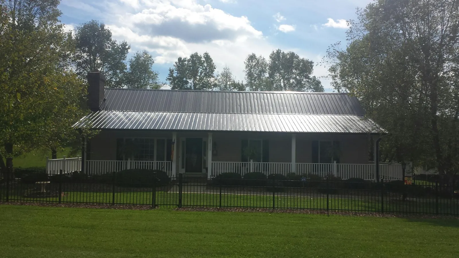 Gray metal roof on a brick ranch with a full width front porch — Gutter Guard Installation work by our crew in Conover